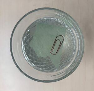 Ein Glas Wasser mit einer schwimmenden Büroklammer